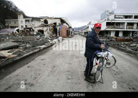 25. März 2011-Kamaishi, Japan-Alter Fahrradmann sammelt seinen Haushalt auf Trümmern und Schlamm, der beim Tsunami-Schlag bedeckt wurde, der zerstörte Minenstadt in Kamaishi am 25. März 2011, Japan. Am 11. März 2011 ereignete sich in Japan ein Erdbeben mit einer Magnitude von 9,0, dem größten in der Geschichte des Landes und einem der fünf mächtigsten, die jemals auf der ganzen Welt verzeichnet wurden. Innerhalb einer Stunde nach dem Erdbeben wurden die Städte, die das Ufer säumten, durch einen massiven Tsunami abgeflacht, der durch die Energie verursacht wurde, die durch das Erdbeben freigesetzt wurde. Mit Wellen von bis zu vier oder fünf Metern Höhe stürzten sie durch Häuser, Städte und Felder der Zivilbevölkerung. (Foto Stockfoto