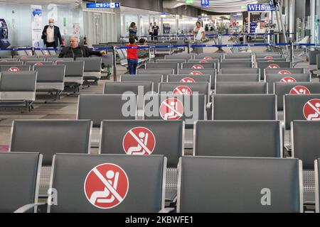 Passagiere, die mit Gesichtsmask warten, am Schalter zum Einsteigen einchecken und leere Sitzplätze mit Schildern blockieren, die sie im Bereich des Gates mit reduziertem Verkehr blockieren. Flug vom Athens International Airport ATH LGAV in Griechenland. Passagiere mit Gesichtsmasken und Schutzmaßnahmen wie Handschuhen, Händedesinfektionsmittel, Sitzblockierung, sozialer Distanzierung, Distanzschildern usw. aufgrund des Coronavirus Covid-19-Pandemieausbruchs, Sicherheitsmaßnahmen, wie sie an den Check-in-Schaltern, am Hauptabflugterminal und an den Gates zu sehen sind. Athen, Griechenland - Juli 2020 (Foto von Nicolas Economou/NurPhoto) Stockfoto