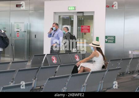 Passagiere, die mit Gesichtsmask warten, am Schalter zum Einsteigen einchecken und leere Sitzplätze mit Schildern blockieren, die sie im Bereich des Gates mit reduziertem Verkehr blockieren. Flug vom Athens International Airport ATH LGAV in Griechenland. Passagiere mit Gesichtsmasken und Schutzmaßnahmen wie Handschuhen, Händedesinfektionsmittel, Sitzblockierung, sozialer Distanzierung, Distanzschildern usw. aufgrund des Coronavirus Covid-19-Pandemieausbruchs, Sicherheitsmaßnahmen, wie sie an den Check-in-Schaltern, am Hauptabflugterminal und an den Gates zu sehen sind. Athen, Griechenland - Juli 2020 (Foto von Nicolas Economou/NurPhoto) Stockfoto