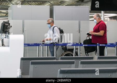 Passagiere, die mit Gesichtsmask warten, am Schalter zum Einsteigen einchecken und leere Sitzplätze mit Schildern blockieren, die sie im Bereich des Gates mit reduziertem Verkehr blockieren. Flug vom Athens International Airport ATH LGAV in Griechenland. Passagiere mit Gesichtsmasken und Schutzmaßnahmen wie Handschuhen, Händedesinfektionsmittel, Sitzblockierung, sozialer Distanzierung, Distanzschildern usw. aufgrund des Coronavirus Covid-19-Pandemieausbruchs, Sicherheitsmaßnahmen, wie sie an den Check-in-Schaltern, am Hauptabflugterminal und an den Gates zu sehen sind. Athen, Griechenland - Juli 2020 (Foto von Nicolas Economou/NurPhoto) Stockfoto