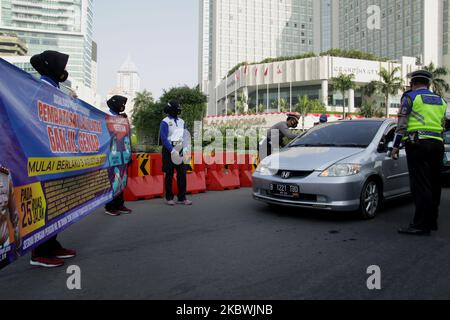 Polizeibeamte des Verkehrsdirektorats der U-Bahn-Polizei von Jakarta entfalteten am 2. August 2020 in den Umkreisbereichen des Hotels Indonesia in Jakarta Spruchbänder mit Informationen über die Wiederverhängung eines ungeraden Verkehrssystems als öffentliche Sozialisierung. Die Regierung von Jakarta beschloss, während der Neuen Normalperiode ein ungeraden Verkehrssystem wieder einzuführen, um die Ausbreitung des Covid-19-Coronavirus zu verhindern, da das Verkehrsministerium von Jakarta berichtete, dass das Verkehrsaufkommen im Fahrzeug aufgrund einer Zunahme öffentlicher Aktivitäten nach der Lockerung durch die Regierung erheblich zugenommen habe Semi-Lock unten p Stockfoto