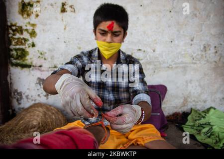 Hindu-Priester mit Schutzmaske und Handschuhen führt am 3. August 2020 während des Janai Purnima Festivals im Pashupatinath Tempel in Kathmandu, Nepal, ein Ritual durch. Das Janai Purnima Festival ist bekannt als das Heilige Faden Festival, bei dem Hindu-Männer, vor allem die Brahmanen und Chettris, ihren jährlichen wechselnden heiligen Faden, der Janai genannt wird, der über der Brust getragen oder um das Handgelenk gebunden wird, durchführen. (Foto von Rojan Shrestha/NurPhoto) Stockfoto