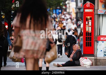 Eine Frau bettelt als Einkäufer, einige tragen Gesichtsmasken, spazieren am 5. August 2020 entlang der Oxford Street in London, England. (Foto von David Cliff/NurPhoto) Stockfoto