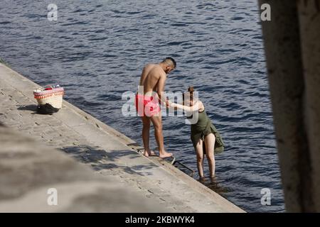 Ein Mann hilft einer Frau, auf die seine zu steigen, um ihren Körper während der Hitzewelle zu erfrischen, die am 9. August 2020 in Paris, Frankreich, angekündigt wurde. (Foto von Mehdi Taamallah/NurPhoto) Stockfoto