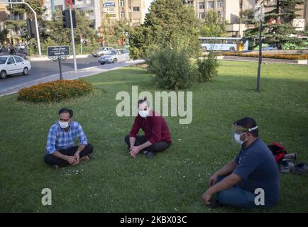 Drei iranische Männer, die Schutzmasken tragen, beobachten am 9. August 2020 nach dem Ausbruch des neuen Coronavirus (COVID-19) im Iran eine soziale Distanzierung, während sie auf einem Platz im Norden Teherans sitzen. (Foto von Morteza Nikoubazl/NurPhoto) Stockfoto