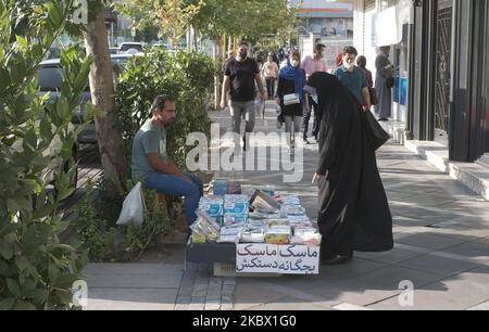 Eine verschleierte iranische Frau, die eine schützende Gesichtsmaske trägt, zeigt auf, während sie bei einem Händler an einer Straße im Norden Teherans nach dem Ausbruch des neuen Coronavirus (COVID-19) im Iran am 9. August 2020 einkauft. (Foto von Morteza Nikoubazl/NurPhoto) Stockfoto