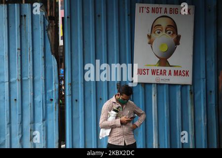 Ein Mann benutzt am 12. August 2020 in Mumbai, Indien, ein Mobiltelefon vor einem „IT’s not A Big Ask, Just wear A Mask“-Banner. Indien ist nach den USA und Brasilien die drittgrößte von der Coronavirus-Pandemie (COVID-19) getroffenen Nation. (Foto von Himanshu Bhatt/NurPhoto) Stockfoto