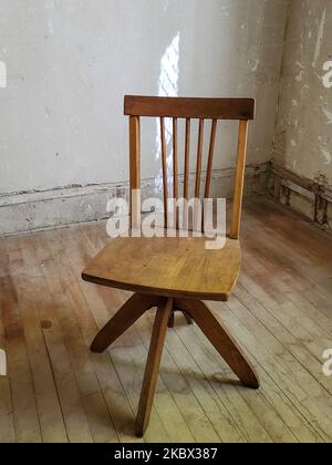 Holzstuhl in einem alten Zimmer mit verzweifelten Wänden und Holzboden Stockfoto