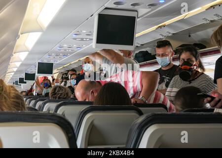 Passagiere mit Gesichtsmasken, die in einem Airbus Aegean A320 einsteigen. Fliegen in einem Aegean Airlines Airbus A320 während der Coronavirus-Pandemie mit obligatorischer Verwendung von Gesichtsmasken für die Passagiere im Flugzeug und am Flughafen. Die Flugbesatzung, die weibliche Flugbegleiterin, trägt auch Sicherheitsausrüstung wie Gesichtsmasken und Handschuhe, während die Mahlzeiten gewechselt werden und eine desinfizierende Serviette bereitgestellt wird. Die Inlandsflugroute ist von Thessaloniki SKG LGTS zum Athens ATH LGAV Airport, der griechischen Hauptstadt. Die griechische Regierung hob das Verkehrsverbot auf, sperrte Quarantänemaßnahmen für Touristen und lockert die Gattungen Stockfoto