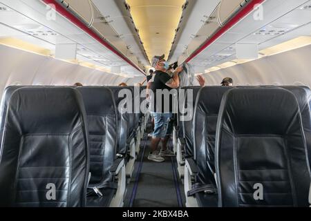 Passagiere mit Gesichtsmasken, die in einem Airbus Aegean A320 einsteigen. Fliegen in einem Aegean Airlines Airbus A320 während der Coronavirus-Pandemie mit obligatorischer Verwendung von Gesichtsmasken für die Passagiere im Flugzeug und am Flughafen. Die Flugbesatzung, die weibliche Flugbegleiterin, trägt auch Sicherheitsausrüstung wie Gesichtsmasken und Handschuhe, während die Mahlzeiten gewechselt werden und eine desinfizierende Serviette bereitgestellt wird. Die Inlandsflugroute ist von Thessaloniki SKG LGTS zum Athens ATH LGAV Airport, der griechischen Hauptstadt. Die griechische Regierung hob das Verkehrsverbot auf, sperrte Quarantänemaßnahmen für Touristen und lockert die Gattungen Stockfoto