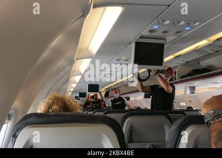 Passagiere mit Gesichtsmasken, die in einem Airbus Aegean A320 einsteigen. Fliegen in einem Aegean Airlines Airbus A320 während der Coronavirus-Pandemie mit obligatorischer Verwendung von Gesichtsmasken für die Passagiere im Flugzeug und am Flughafen. Die Flugbesatzung, die weibliche Flugbegleiterin, trägt auch Sicherheitsausrüstung wie Gesichtsmasken und Handschuhe, während die Mahlzeiten gewechselt werden und eine desinfizierende Serviette bereitgestellt wird. Die Inlandsflugroute ist von Thessaloniki SKG LGTS zum Athens ATH LGAV Airport, der griechischen Hauptstadt. Die griechische Regierung hob das Verkehrsverbot auf, sperrte Quarantänemaßnahmen für Touristen und lockert die Gattungen Stockfoto