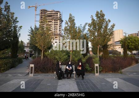 Nach dem Ausbruch der COVID-19 im Iran, 13. August 2020, sitzen verschleierte iranische Frauen mit Schutzmasken auf einer Bank im künstlichen See-Komplex Chitgar im Nordwesten Teherans. Die Menschen in Teheran scheinen sich an das neue Coronavirus gewöhnt zu haben und verwenden die Maske als tägliche Routine. (Foto von Morteza Nikoubazl/NurPhoto) Stockfoto