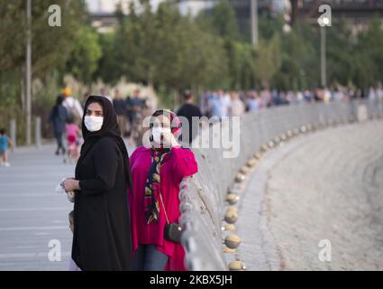 Zwei iranische Frauen, die Schutzmasken tragen, stehen nach dem Ausbruch der COVID-19 im Iran am 13. August 2020 im künstlichen See-Komplex Chitgar im Nordwesten Teherans. Die Menschen in Teheran scheinen sich an das neue Coronavirus gewöhnt zu haben und verwenden die Maske als tägliche Routine. (Foto von Morteza Nikoubazl/NurPhoto) Stockfoto