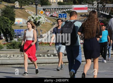Die Menschen gehen durch den Unabhängigkeitsplatz, die Straße der Himmlischen Hundert mit einer riesigen Nationalflagge von Belarus, die auf der Brücke über sie im Hintergrund hängt, in Kiew, Ukraine, 17. August 2020. Die Behörden der Stadt Kiew hängten die Nationalflagge von Belarus über dem zentralen Eingang zum Stadtrat zur Unterstützung des belarussischen Volkes auf. Außerdem hängen an mehreren anderen Orten in Kiew riesige Flaggen von Belarus. (Foto von Sergii Chartschenko/NurPhoto) Stockfoto
