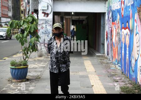 Ein Mann geht an dem von Bambang und seinen Freunden auf der Straßenmauer in der Nähe des Straßenmalstudios von Bambang gemalten Wandgemälde vorbei, das am 17. August 2020 anlässlich des indonesischen Unabhängigkeitstages 75. in Jakarta, Indonesien, gemalt wurde. Bambang Tridoyo (63), Street Painting Artist. Seine Karriere begann er seit 1975. Als Bewunderer von Indonesiens Gründervater Sukarno sind viele Werke Bambangs von Geschichten und Heldenfiguren inspiriert. Er verkauft nicht nur seine Bilder, sondern übernimmt auch Porträtmalereien für seine Kunden. Die Covid-19-Pandemie, die Indonesien seit der en heimgesucht hat Stockfoto