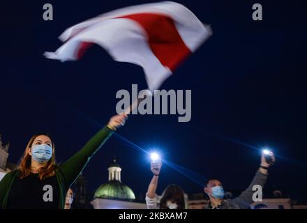 Ein Protestler hält eine weiß-rot-weiße weißrussische Oppositionsflagge. Mitglieder der lokalen belarussischen Diaspora, Aktivisten und lokale Unterstützer trafen sich am Dienstagabend, um ihre Solidarität mit den belarussischen Menschen während des Protestes „Solidarität mit Belarus“, der auf dem Hauptmarkt in Krakau organisiert wurde, auszudrücken. Am 18. August 2020 in Krakau, Polen. (Foto von Artur Widak/NurPhoto) Stockfoto