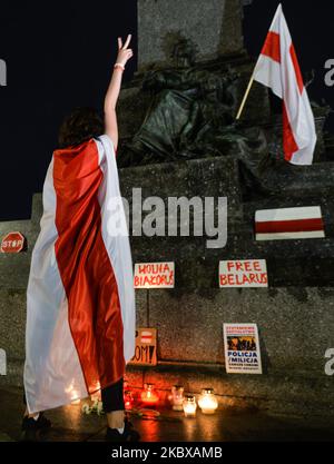 Während der weißrussischen Nationalhymne hält ein Protestler eine weiß-rot-weiße weißrussische Oppositionsflagge. Mitglieder der lokalen belarussischen Diaspora, Aktivisten und lokale Unterstützer trafen sich am Dienstagabend, um ihre Solidarität mit den belarussischen Menschen während des Protestes „Solidarität mit Belarus“, der auf dem Hauptmarkt in Krakau organisiert wurde, auszudrücken. Am 18. August 2020 in Krakau, Polen. (Foto von Artur Widak/NurPhoto) Stockfoto