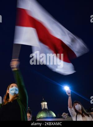 Ein Protestler hält eine weiß-rot-weiße weißrussische Oppositionsflagge. Mitglieder der lokalen belarussischen Diaspora, Aktivisten und lokale Unterstützer trafen sich am Dienstagabend, um ihre Solidarität mit den belarussischen Menschen während des Protestes „Solidarität mit Belarus“, der auf dem Hauptmarkt in Krakau organisiert wurde, auszudrücken. Am 18. August 2020 in Krakau, Polen. (Foto von Artur Widak/NurPhoto) Stockfoto