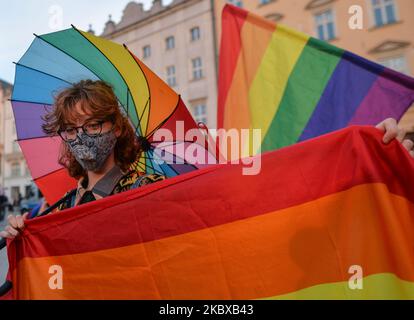 Ein Pro-LGBT-Protestler hält während des Protestes eine Regenbogenfahne und einen Regenschirm. Rechtsextreme Nationalisten und Pro-Life-Aktivisten organisierten einen Protest gegen den LGBT neben dem Adam-Mickiewicz-Denkmal auf dem Krakauer Hauptmarkt. Auf der gegenüberliegenden Seite des Platzes organisierten LGBT-Aktivisten und Antifaschisten einen Gegenprotest. Am 19. August 2020 in Krakau, Woiwodschaft Kleinpolen, Polen. (Foto von Artur Widak/NurPhoto) Stockfoto