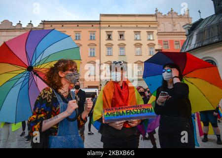 Pro-LGBT-Demonstranten halten Regenbogenfahnen und Regenschirme während des Protestes. Rechtsextreme Nationalisten und Pro-Life-Aktivisten organisierten einen Protest gegen den LGBT neben dem Adam-Mickiewicz-Denkmal auf dem Krakauer Hauptmarkt. Auf der gegenüberliegenden Seite des Platzes organisierten LGBT-Aktivisten und Antifaschisten einen Gegenprotest. Am 19. August 2020 in Krakau, Woiwodschaft Kleinpolen, Polen. (Foto von Artur Widak/NurPhoto) Stockfoto