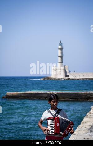 Ein kleines Mädchen spielt am 22. August 2020 vor dem Leuchtturm des Alten venezianischen Hafens in Chania, Kreta, Griechenland, Akkordeon. Seit über 5 Jahrhunderten steht der Leuchtturm des alten venezianischen Hafens von Chania, während er sich zu einem Erkennungszeichen der Stadt auf der ganzen Welt entwickelt hat. (Foto von Nikolas Kokovlis/NurPhoto) Stockfoto