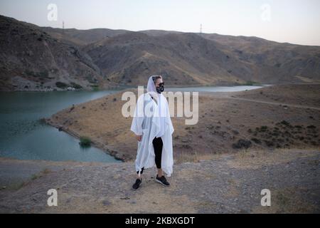 Eine iranische Frau, die eine schützende Gesichtsmaske trägt, posiert für ein Foto, während sie am 23. August 2020 in der Nähe eines Sees im Stadtteil Lavasan im Nordosten Teherans steht. Iraner, die die COVID-19 und die neuen Normalen wie das Tragen von Schutzmasken und die soziale Distanzierung leid sind, besuchen die grüne Nachbarschaft von Lavasan im Nordosten von Teheran, um die Tage vor dem neuen Coronavirus zu erleben. (Foto von Morteza Nikoubazl/NurPhoto) Stockfoto