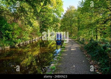 Eine ruhige Szene eines Schmalbootes, das im Frühherbst am Llangollen Canal in Clwyd, Wales, unter Bäumen festgemacht ist. Stockfoto