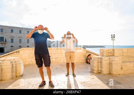 Zwei Herren tragen Masken, bevor sie die Kathedrale von Trani betreten, um eine Ansteckung von Covid-19 in Trani am 28. August 2020 zu vermeiden. In Apulien nehmen die Infektionsfälle mit dem Covid-19-Virus zu. Trani ist eine der am wenigsten von Covid-19-Infektionen betroffenen Städte, und Menschen und Touristen genießen das Meer, die Kathedrale, unter Einhaltung von Sicherheitsmaßnahmen wie sozialer Distanzierung und das Tragen einer Maske. (Foto von Davide Pischettola/NurPhoto) Stockfoto