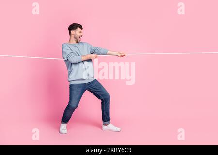 Profil Seite Ganzkörper Foto von bestimmten Kerl ziehen String gewinnen isoliert auf Pastellfarben Hintergrund Stockfoto