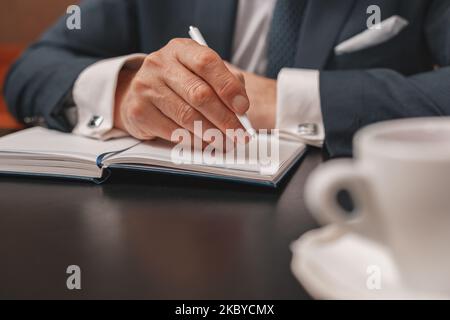 Nahaufnahme der Hände eines Geschäftsmannes, die sich während des Meetings Notizen im Tagebuch machen Stockfoto