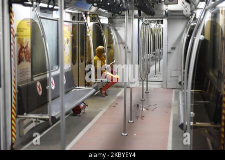 Eine Frau liest während eines Coronavirus-Notfalls in Kalkutta, Indien, am 09. September 2020 ein Papier in einem Metrofach. Ein Mann desinfiziert den Sitzbereich einer U-Bahn-Station während eines Coronavirus-Notfalls in Kalkutta, Indien, am 09. September 2020. Indiens Infektion mit dem Coronavirus stieg laut indischen Medienberichten auf 4,3 Millionen an. (Foto von Indranil Aditya/NurPhoto) Stockfoto
