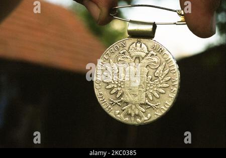 Hunedoara County, Rumänien, 2003. Einheimische Person, die eine Münze aus dem precious18.. Jahrhundert zeigt (Maria Theresia Taler), mit dem gekrönten doppelköpfigen Kaiseradler von Österreich (Habsburger Monarchie). Stockfoto