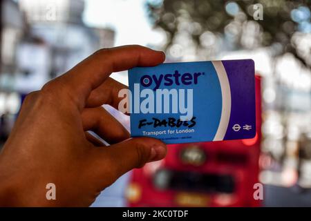 London, England - Juli 07 2017: Hand mit der blauen Oyster-Karte hinter dem roten Doppeldecker Stockfoto