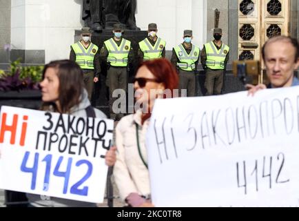 Die Soldaten der Nationalgarde, die Schutzmasken tragen (auf dem Hintergrund), blicken am 29. September 2020 in der Nähe des ukrainischen Parlaments in Kiew, Ukraine, auf einen Protest gegen die Zwangsimpfung und gegen Einschränkungen zur Bekämpfung der Ausbreitung des COVID-19-Coronavirus, einschließlich des Tragens von Masken und Sperren. Die Demonstranten fordern die Gesetzgeber auf, das Gesetz Nr. 4142 „über das öffentliche Gesundheitssystem“ abzulehnen, das laut den Organisatoren des Protestes die obligatorische Impfung von Kindern und Erwachsenen vorsieht. (Foto von STR/NurPhoto) Stockfoto