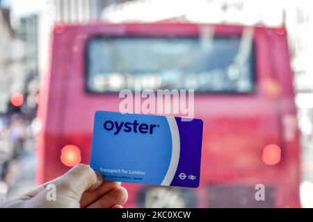 London, England - Juli 07 2017: Hand mit der blauen Oyster-Karte hinter dem roten Doppeldecker Stockfoto