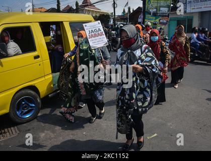 Einige der Batik-Handwerker und Modedesigner in Batik-Kleidung zeigen ihre Arbeiten der Öffentlichkeit am 02. Oktober 2020 auf einer Autobahn in Karangploso City, Malang, Ost-Java. Diese Aktivität ist eine Kampagne für die Erhaltung des indonesischen Batik-Kulturerbes sowie eine Kampagne für die Disziplin der Gesundheitsprotokolle während des Covid-19-Ausbruchs für die Gemeinschaft. (Foto von Aman Rochman/NurPhoto) Stockfoto