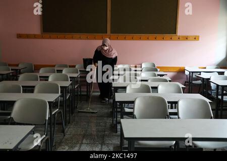 Ein palästinensischer Arbeiter, der eine Gesichtsmaske trägt, desinfiziert vor Beginn eines neuen Studienjahres ein Klassenzimmer, angesichts der Besorgnis über die Ausbreitung des COVID-19 in Khan Younis im südlichen Gazastreifen am 4. Oktober 2020. (Foto von Majdi Fathi/NurPhoto) Stockfoto