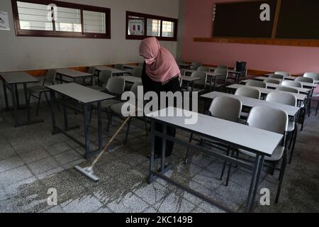 Ein palästinensischer Arbeiter, der eine Gesichtsmaske trägt, desinfiziert vor Beginn eines neuen Studienjahres ein Klassenzimmer, angesichts der Besorgnis über die Ausbreitung des COVID-19 in Khan Younis im südlichen Gazastreifen am 4. Oktober 2020. (Foto von Majdi Fathi/NurPhoto) Stockfoto