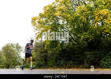 Tim Jackson, ein Teilnehmer des Virgin Money Virtual London Marathon, wird am 4. Oktober 2020 bei kaltem Regenwetter im Dulwich Park in South London, England, laufen sehen. Aufgrund der Covid-19-Pandemie war der London Marathon für die Öffentlichkeit virtuell. Die Teilnehmer laufen an Orten der Wahl und verfügen über eine mobile Anwendung als Überwachungssystem. Familie und Freunde nahmen oft kürzere Distanzen ein, um den Läufer zu unterstützen. (Foto von Dominika Zarzycka/NurPhoto) Stockfoto