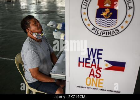 Ein Gesundheitsfachkraft sammelt bei einem kostenlosen COVID-19-Test für Marktverkäufer auf einem öffentlichen Markt in Manila, Philippinen, am 6. Oktober 2020 Abstrichproben von einem Mann. (Foto: Lisa Marie David/NurPhoto) Stockfoto