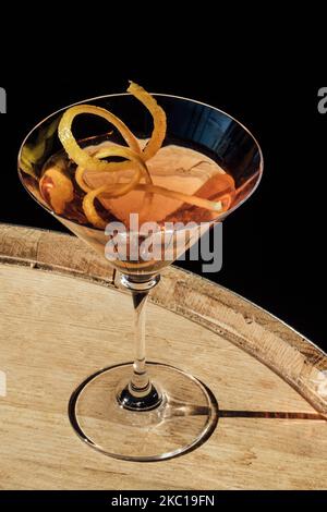 Pink martini-Cocktail mit langer Zitronenverdrehung, der auf einem Whiskey-Fass in der Sonne sitzt Stockfoto