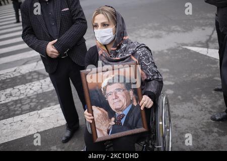 Eine iranische Frau mit einer schützenden Gesichtsmaske sieht auf, als sie am 9. Oktober 2020 auf dem Friedhof Behesht-e-Zahra im Süden Teherans ein Porträt des ikonischen Sängermeisters der persischen traditionellen Musik, des persischen Kalligraphen und humanitären Aktivisten Mohammad-Reza Shajarian hält. (Foto von Morteza Nikoubazl/NurPhoto) Stockfoto