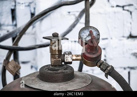 Alte Gasflaschen zum Schweißen und Schneiden. Rostige Propan- und Sauerstofftanks. Werkzeuge für die metallverarbeitende Industrie. Verlassene Baustelle. Stockfoto