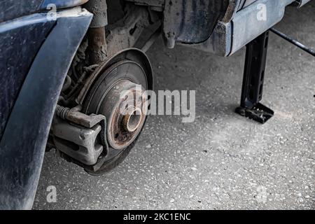 Der Automechaniker wechselt das Rad des alten Autos. Der Mann wechselt nach dem Ausfall den Reifenschaden. Nothilfe am Straßenrand. Nahaufnahme des Autorads. Stockfoto