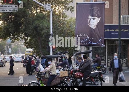 Motorradfahrer halten unter einem Porträt des ikonischen iranischen Sängers, des Meisters der persischen traditionellen Musik, des persischen Kalligraphen und humanitären Aktivisten Mohammad-Reza Shajarian, das am 10. Oktober 2020 an einer Plakatwand auf einer Straße im Geschäftsviertel von Teheran aufgehängt wird. Mohammad-Reza Shajarian wurde nach den Unruhen im Iran nach den Präsidentschaftswahlen nach 2012 vom Singen und Abhalten eines Konzerts verboten, da er ein Lied zur Unterstützung der iranischen Demonstranten gesungen hat. (Foto von Morteza Nikoubazl/NurPhoto) Stockfoto