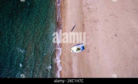 Vertikale Luftaufnahme eines Mannes, der mit einem Twin-Tip-Board und einem Kite zum Kiteboarden am strand von caesarea, Israel, unterwegs ist Stockfoto