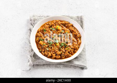 Keema-Schälchen in Schale auf hellem Steingrund. Indische und pakistanische Gerichte. Nahaufnahme Stockfoto