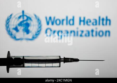 Die medizinische Spritze ist mit dem Logo der Weltgesundheitsorganisation auf einem Bildschirm im Hintergrund auf diesem Illustrationsfoto zu sehen, das am 12. Oktober 2020 in Polen aufgenommen wurde. (Foto-Illustration von Jakub Porzycki/NurPhoto) Stockfoto