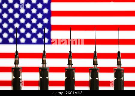 Medizinische Spritzen sind mit amerikanischer Flagge im Hintergrund auf diesem Bild zu sehen, das am 12. Oktober 2020 in Polen aufgenommen wurde. (Foto-Illustration von Jakub Porzycki/NurPhoto) Stockfoto