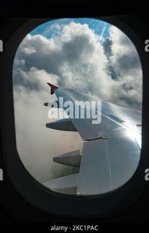 Flügelansicht aus dem Fenster des Flugzeugs mit Wolken während des Fluges. Fliegen mit einem Flugzeug des Typs Lauda Airbus A320 mit der Registrierung 9H-LMJ während der Coronavirus-Pandemie Covid-19 mit Passagier- und Crew-Personal im Gesichtsschutz. Laudamotion oder Lauda ist eine österreichische Low-Cost-Fluggesellschaft, die Ryanair gehört und die Ryanair-Codes FR für IATA, RYR für ICAO und RYANAIR-Rufzeichen verwendet. Die Billigfluggesellschaft hat ihren Sitz am Vienna International Airport VIE LOWW oder am Flughafen Wien-Schwechat in Österreich mit einer Flotte von 28 Airbus-Flugzeugen. Wien, Österreich am 12. Oktober 2020 (Foto von Nicolas Economou/NurPhoto) Stockfoto